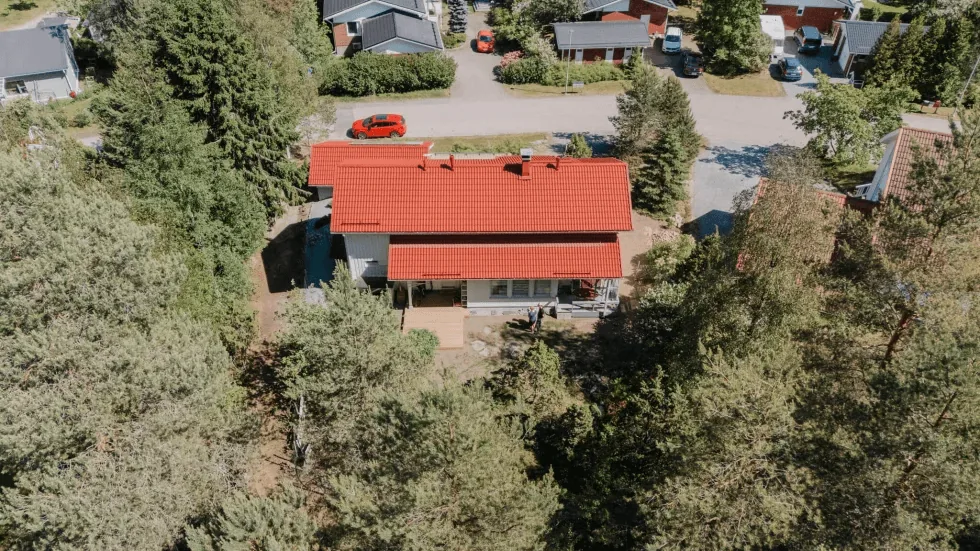 Tiilitalon ulkokuva, vihreä piha ja sininen taivas