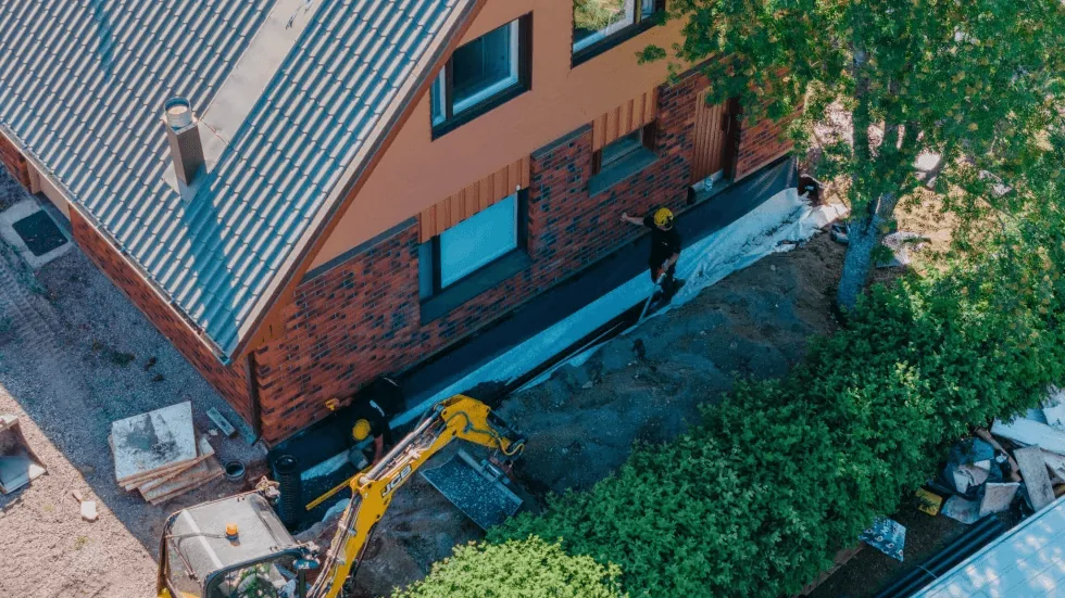 Tiilitalon ulkokuva, vihreä piha ja sininen taivas