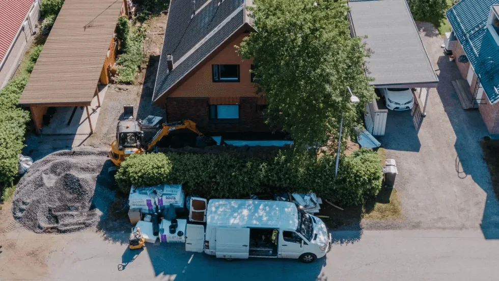 Tiilitalon ulkokuva, vihreä piha ja sininen taivas