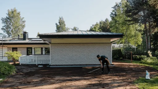 Valkoinen omakotitalo ja työntekijä työmaalla