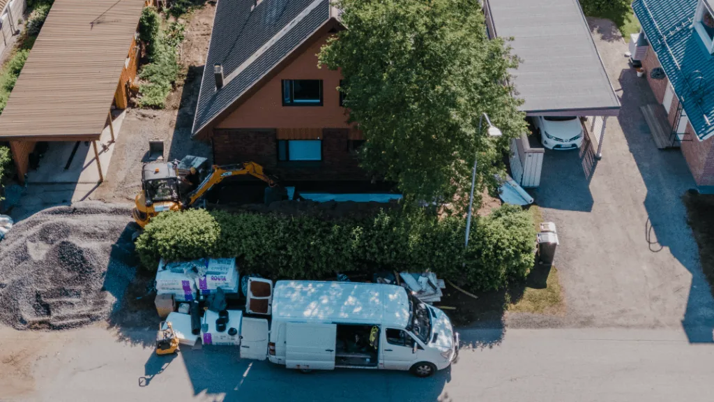 Tiilitalon ulkokuva, vihreä piha ja sininen taivas