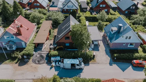 Tiilitalon ulkokuva, vihreä piha ja sininen taivas